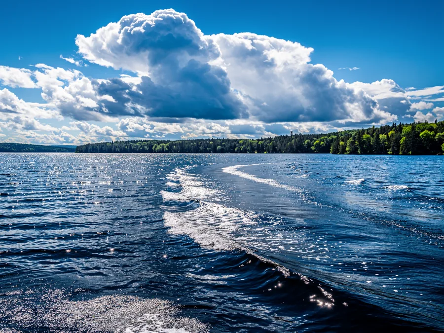 A large deep blue inland lake on a breezy afternoon, light chop on open water under tall summer clouds